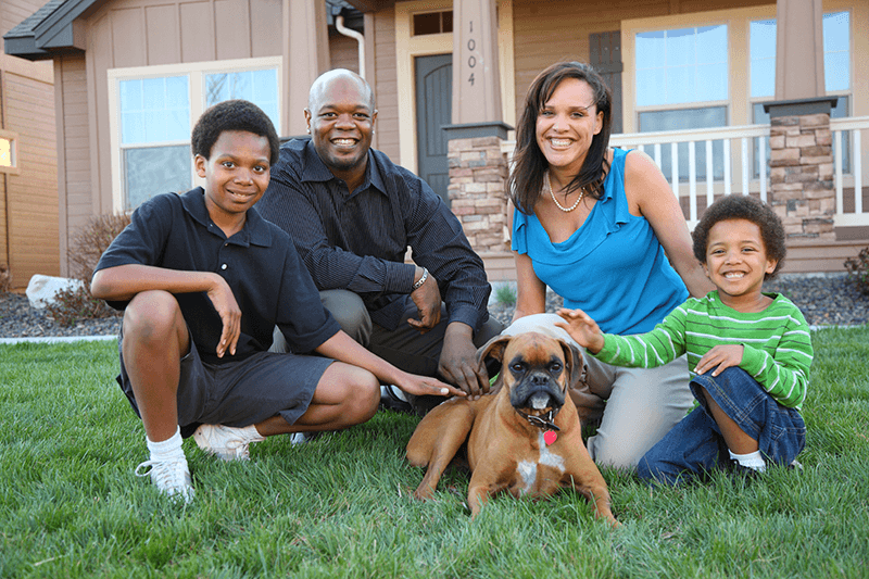 A family of four with their dog posing in front of their house which is insured by D.G Bevan Ontario Insurance Brokers- Personal Home Insurance
